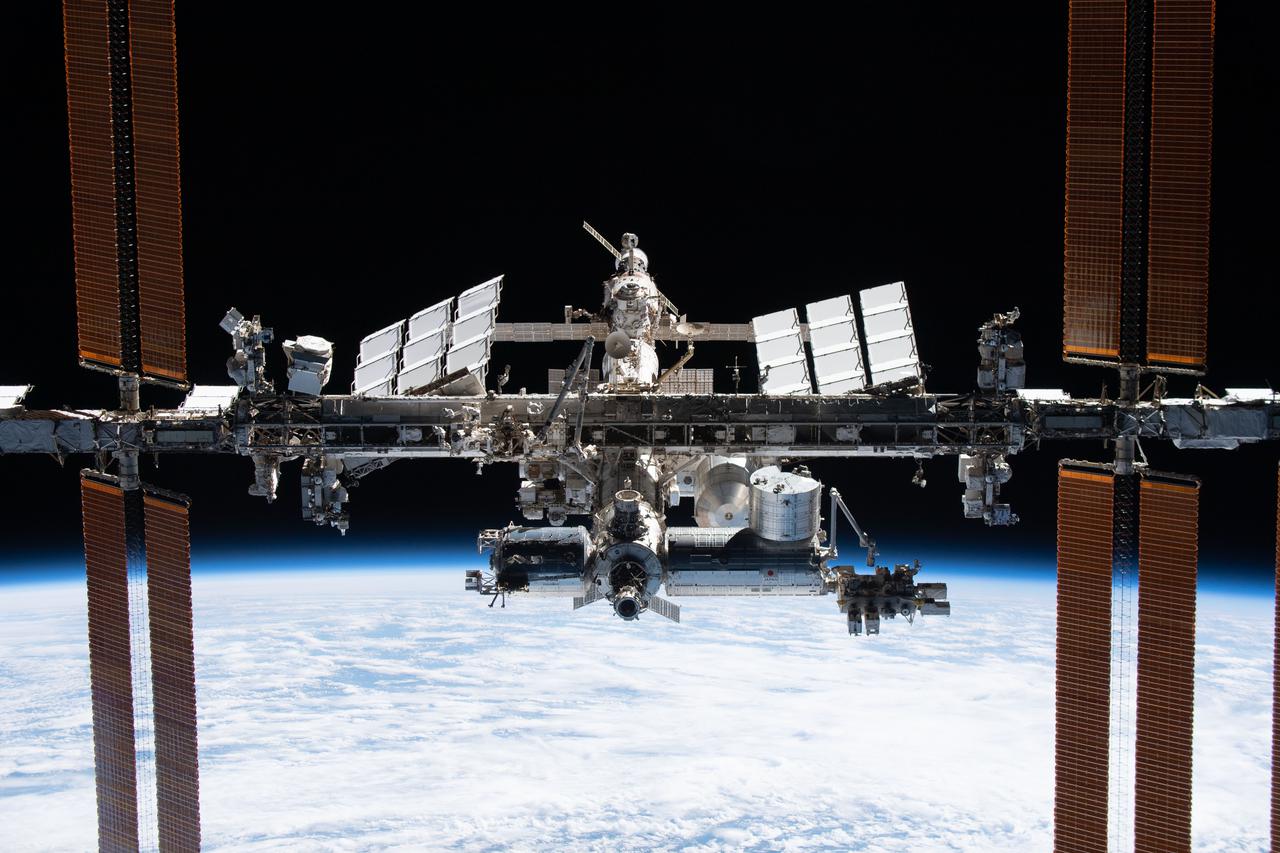 The International Space Station in orbit, solar arrays extended, Earth below